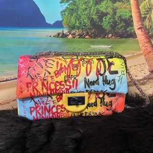 Large graffiti handbag with black chain strap.